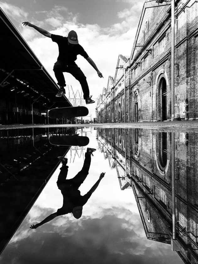 This image was captured at the Eveleigh Carriage Works in Sydney. After heavy rain, the puddles at this industrial location make for awesome reflections, and the zig-zag roof line is such a unique feature of this building. An added bonus here was the skateboarder willing to do a few flips. And, lucky for me, I was able to take the picture at the right moment. Apple iPhone 15 Plus. 1/690s @ f1.6, ISO 50.